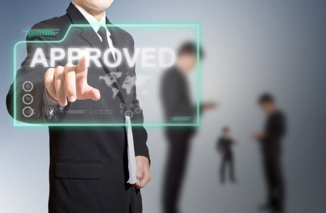 Photo – a man in a suit presses a folder marked ‘approved’ 