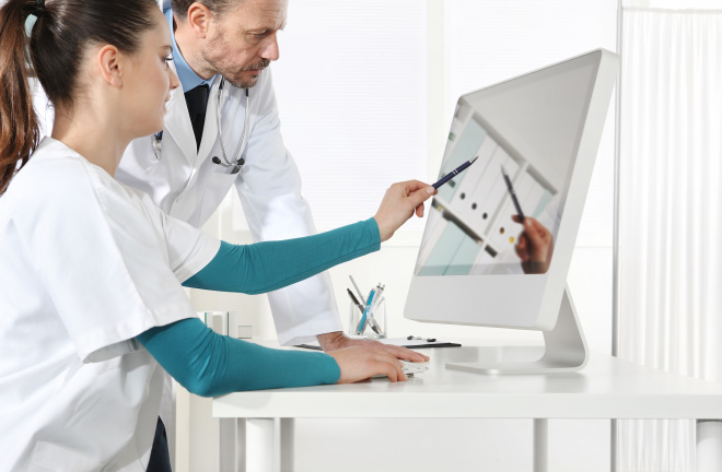 Photo – Two doctors discuss information on a screen.