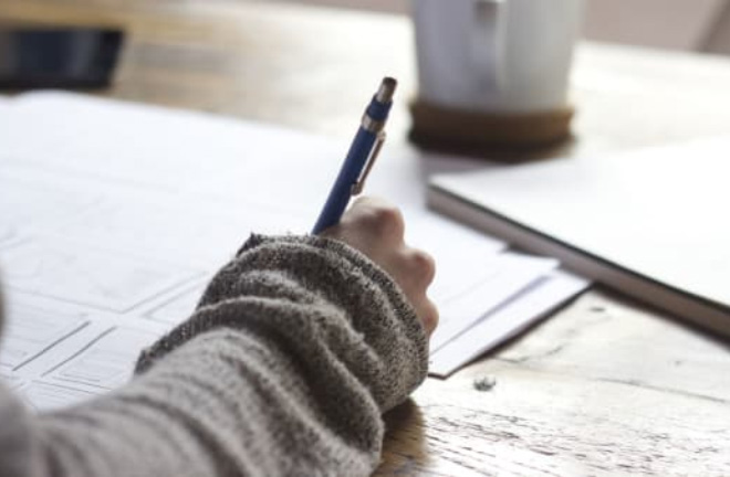 Photo – a closeup of a person filling in a document with a pen