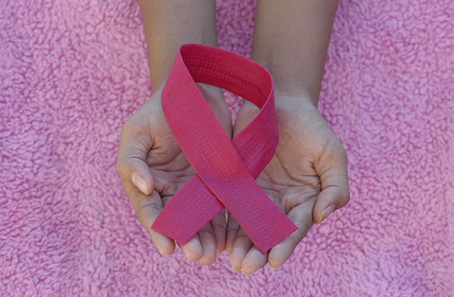 photo - closeup of someone's hands holding a pink ribbon